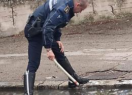 Ingresso della scuola allagato, un agente della Polizia Locale libera le caditoie